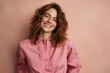 Portrait of a smiling young woman in pink shirt on pink background