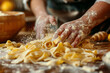 Close-up of hands making fresh fettuccine pasta with flour on a rustic kitchen table.