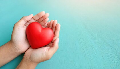 hands holding red heart on aqua background, heart health, donation, CSR concept, world heart