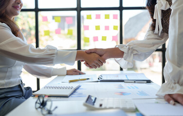 Two businesswoman shaking hands for success. Handshake. Collaboration, teamwork, friendship. Meeting of financial business partners, paperwork, calculations, investments, company partnerships.