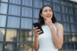 © crizzystudio - Confident and positive Asian online businesswoman using smartphone to relax with mobile application, use business chat and connect with customers outside online market place. Excellent profits.