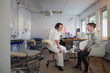 © Johnér - Smiling gay boy consulting female gynecologist while sitting on chair in clinic