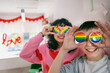 © Johnér - Smiling teenage LGBTQIA friends covering eyes with rainbow badges in clinic