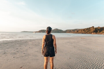 Wall Mural - Woman walking along the beach in the evening