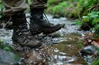 person rinsing muddy hiking boots in a stream