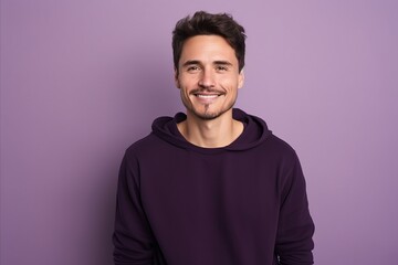 Wall Mural - Portrait of a handsome young man smiling at camera while standing against purple background