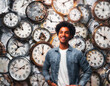 Portrait of a young african american man standing in front of a wall full of clocks.
