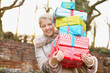 © fStop - Young Woman Holding Stack of Christmas Presents Outdoors