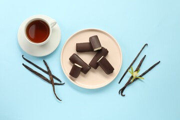 Canvas Print - Glazed curd cheese bars, vanilla pods and tea on light blue background, flat lay