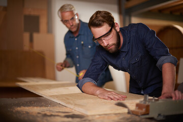 Canvas Print - Wood, father and son in a workshop, architect and carpenter with renovation or safety glasses with protection. Parent, men or teamwork with construction or building with planning for project or gear