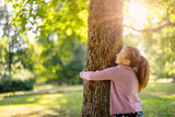 Fototapeta Na ścianę - Cute little girl hugging tree in the natural park.