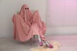 © New Africa - Glamorous ghost. Woman in pink sheet and high heel shoes on armchair indoors, space for text
