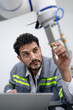 © Nassorn - Latino robotic development engineer working robot arm connection control at electronic futuristic science laboratory. Hispanic technician learning innovation machine in automated engineering academy.