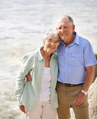 Wall Mural - Senior, couple and happy portrait at beach for retirement vacation or anniversary to relax with love, care and commitment with support. Elderly man, woman and together by ocean for peace on holiday.