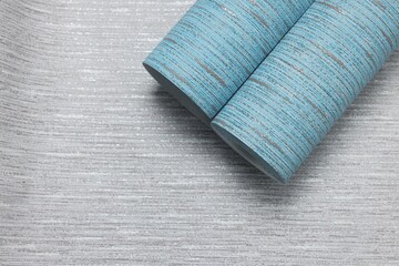 Wall Mural - Light blue wallpaper roll on grey sample, top view. Space for text