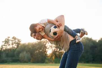 Wall Mural - Soccer ball in hands. Father and little son are playing and having fun outdoors