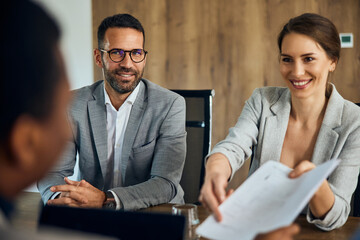 Business people interviewing with a client, giving him a contract to sign.