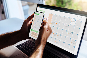 man looking at calendar on phone and laptop, early in the morning for planning the day. digital sche