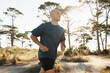 © Katie/peopleimages.com - Fitness, running and man on road in forest for health, wellness and strong body development. Workout, exercise and runner on path in nature for marathon training, performance and morning challenge.