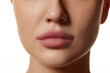 Cropped close-up image of beautiful female face, plump lips with nude lipsticks makeup isolated against white studio background. Lip augmentation. Concept of beauty, cosmetology, cosmetics, skin care