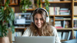 Smiling Young Woman with Headphones Using Laptop in Plant-Filled Room