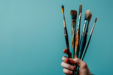 artist holding paintbrushes, isolated on a soft blue background, capturing creativity and artistry