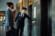 © Drazen - Happy hotel attendant and black businessman waiting for elevator in lobby,