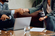 © Drazen - Close up of coworkers handshaking during business meeting in hotel lobby.