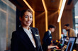 © Drazen - Happy female concierge at front desk in hotel looking at camera.