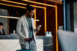 © Drazen - Happy black man using cell phone in hotel lobby.