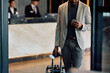© Drazen - Close up of black man texting on mobile phone after checking in at hotel.