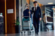 © Drazen - Happy bellboy pushing luggage cart with guest's suitcases in hotel.