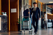 © Drazen - Happy hotel attendant luggage cart through lobby and looking at camera.