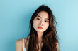 Portrait of a pretty young asian woman with long dark hair on a blue background