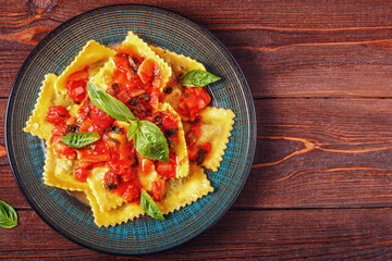 Wall Mural - Ravioli with tomato sauce and basil on dark background.