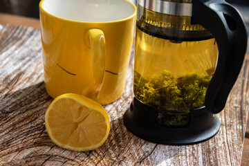 Wall Mural - Teapot (French press) with half lemon and teapot at wooden table on the balcony, morning tea time, aromatic aromatherapy fresh and herbal, organic tea from farm. In background neighborhood buildings