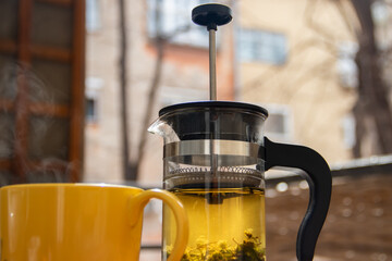 Wall Mural - Teapot (French press) with half lemon and teapot at wooden table on the balcony, morning tea time, aromatic aromatherapy fresh and herbal, organic tea from farm. In background neighborhood buildings