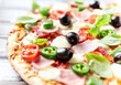 © Eugeniusz Dudziński - Pizza with ham, mozzarella cheese, cherry tomatoes, green and jalapeno pepper, black olives and fresh basil. Bright background. Close up.