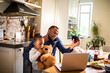 © Marko Geber - Single father having breakfast with his two young daughters while talking on the phone and working on his laptop