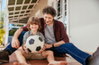 © Marko Geber - Father and son playing with a soccer ball on house porch