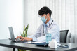 © Freedomz - Male doctor in medical face mask using laptop to searching information about treatment the symptoms of patient