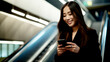 © PETR BABKIN - Business Woman on an Escalator Looking at her Mobile Phone