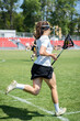 Lacrosse competition - Women's lacrosse player running, holding a lacrosse stick.