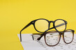 Vision test chart and glasses on yellow background, space for text