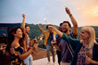 © Drazen - Cheerful friends using sparklers while dancing during summer party on patio at sunset.