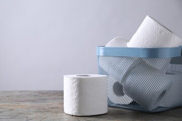 Wall Mural - Toilet paper rolls in basket on textured table near light grey wall, space for text