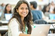 © LimeSky - Picture of an attractive smart Indian Asian student in a university classroom smiling while using a laptop