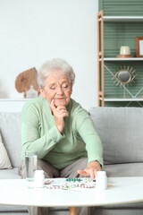 Sticker - Thoughtful senior woman with pills at home