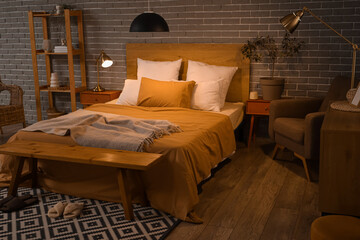 Canvas Print - Interior of bedroom with armchair, glowing lamps and wooden bench at night