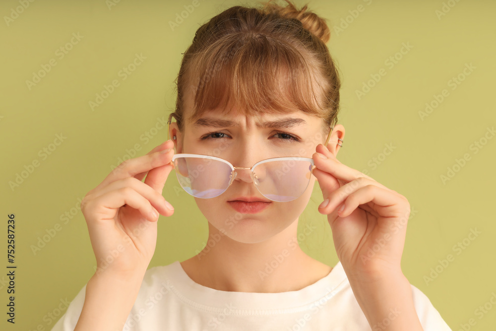 Young woman with eyeglasses squinting on green background, closeup. Glaucoma awareness month